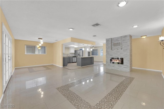 unfurnished living room with baseboards, a tiled fireplace, visible vents, and light tile patterned floors