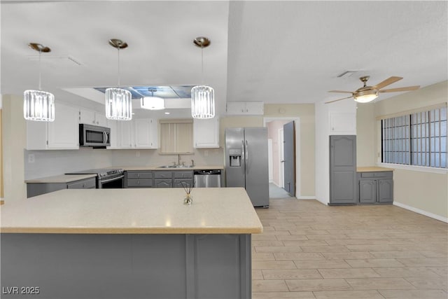 kitchen featuring appliances with stainless steel finishes, gray cabinets, a ceiling fan, and a sink