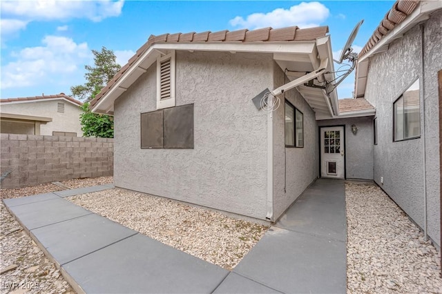 view of home's exterior with stucco siding, fence, and a patio