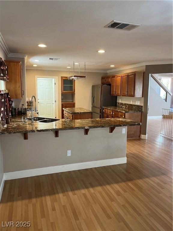 10974 Fintry Hills St, Las Vegas, NV 89141 - kitchen with brown cabinetry, visible vents, a sink, stainless steel fridge, and ornamental molding