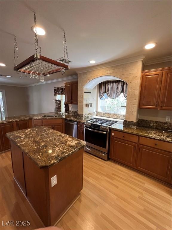 10974 Fintry Hills St, Las Vegas, NV 89141 - kitchen featuring a kitchen island, appliances with stainless steel finishes, ornamental molding, and light wood-type flooring