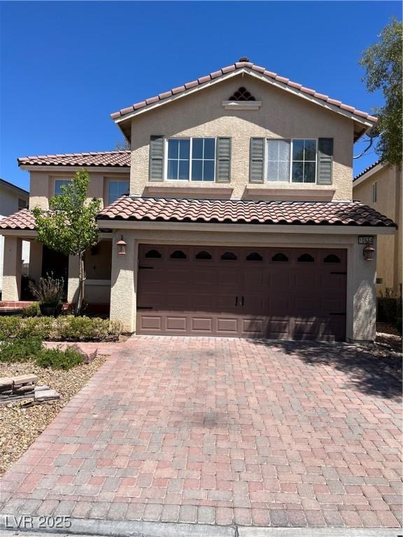 10974 Fintry Hills St, Las Vegas, NV 89141 - mediterranean / spanish house with an attached garage, decorative driveway, stucco siding, and a tile roof