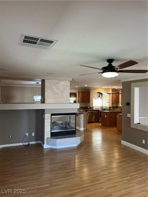 10974 Fintry Hills St, Las Vegas, NV 89141 - unfurnished living room featuring a multi sided fireplace, ceiling fan, visible vents, crown molding, and light wood-style floors
