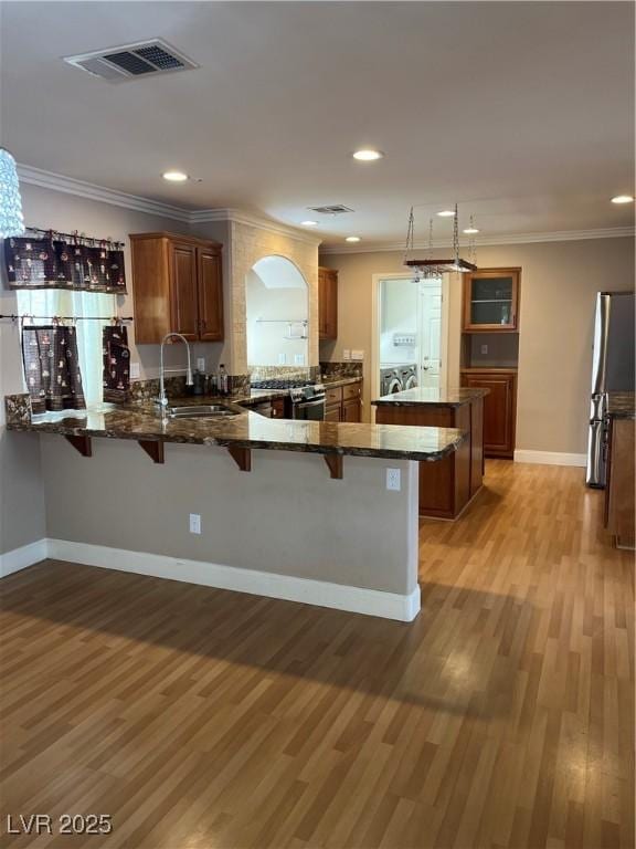 10974 Fintry Hills St, Las Vegas, NV 89141 - kitchen with appliances with stainless steel finishes, a sink, a breakfast bar area, a peninsula, and visible vents
