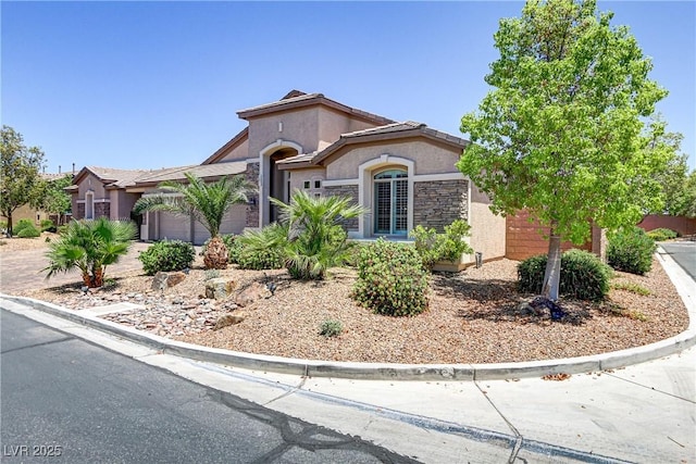 mediterranean / spanish-style house with stucco siding, stone siding, and a garage
