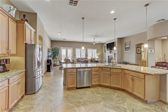 kitchen featuring visible vents, a sink, open floor plan, arched walkways, and stainless steel appliances