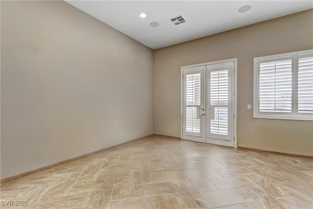 spare room featuring baseboards, french doors, and visible vents