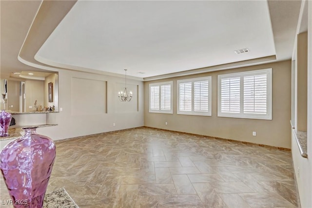unfurnished living room with baseboards, visible vents, and an inviting chandelier