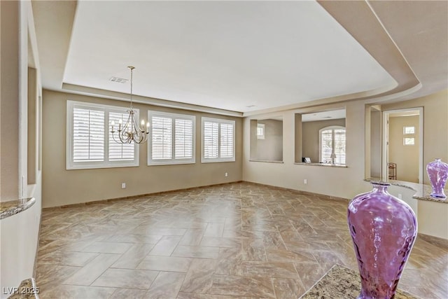 interior space featuring a tray ceiling, a notable chandelier, baseboards, and visible vents