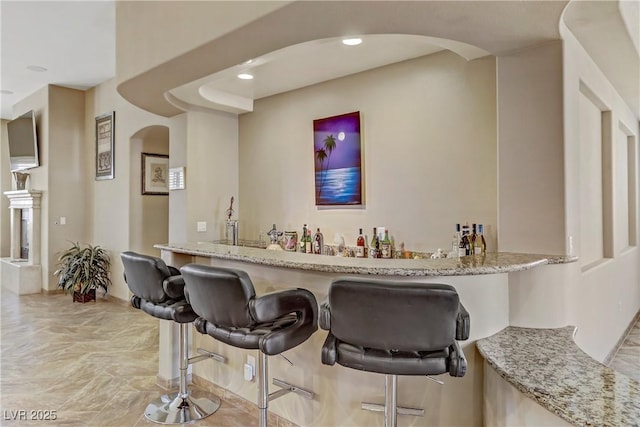 bar featuring recessed lighting, arched walkways, and wet bar