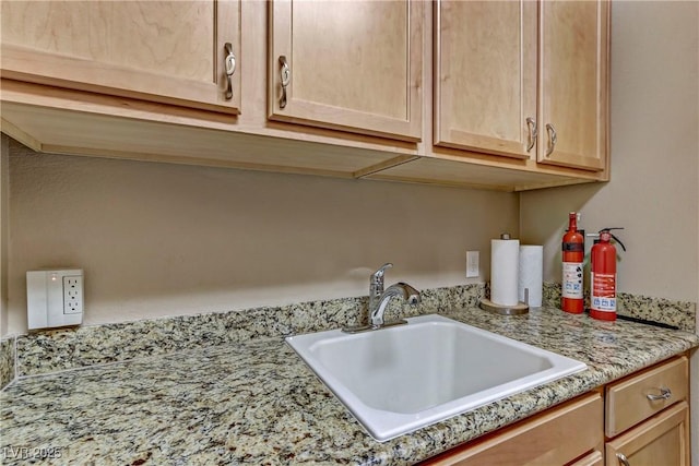 details with light stone counters, a sink, and light brown cabinetry