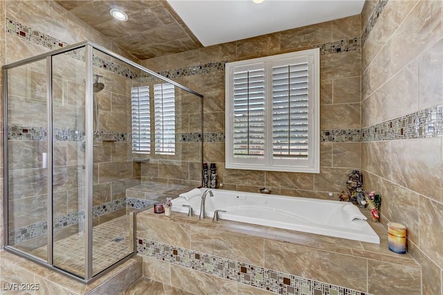 full bath featuring a healthy amount of sunlight, tile walls, a stall shower, and a bath
