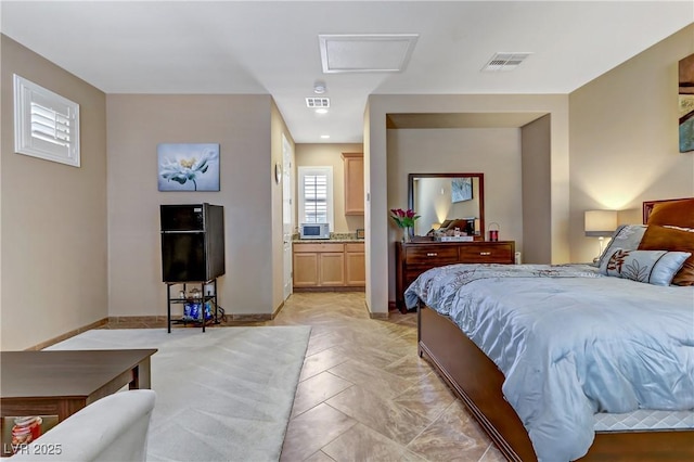 bedroom featuring baseboards, attic access, ensuite bath, and visible vents
