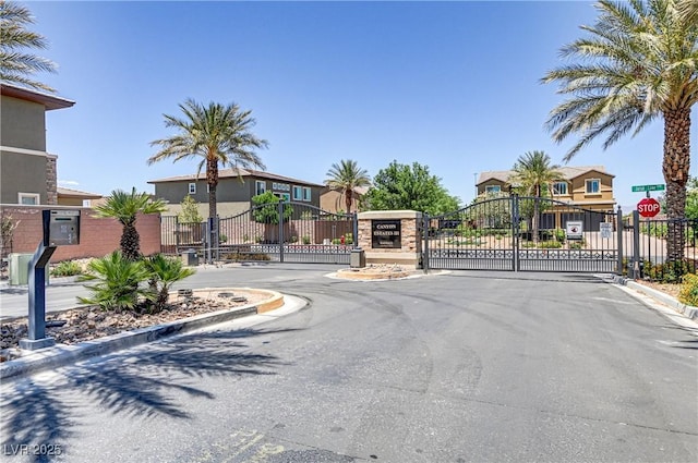 view of road featuring traffic signs, a gated entry, curbs, and a gate