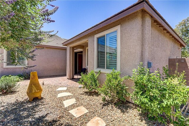 view of front of house with fence, a patio area, and stucco siding