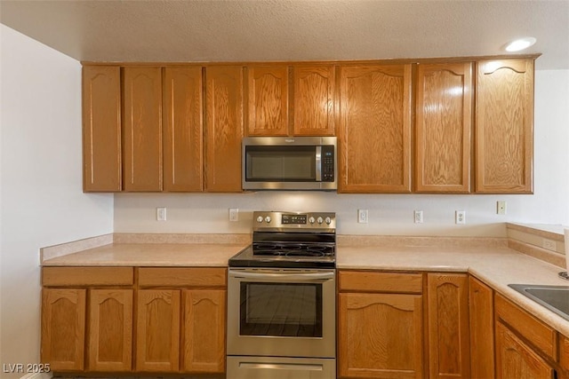 kitchen with light countertops, appliances with stainless steel finishes, and brown cabinetry