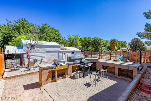 view of patio featuring fence, grilling area, a wooden deck, and exterior kitchen