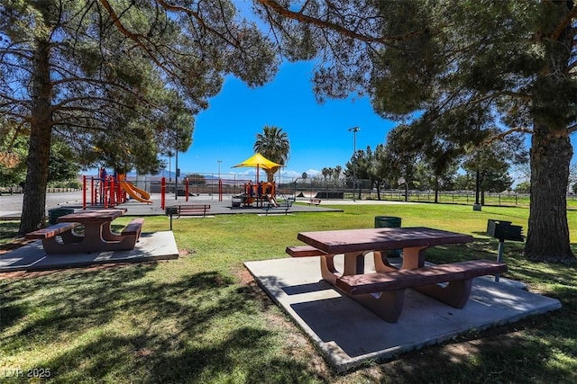 view of community featuring a lawn, fence, and playground community