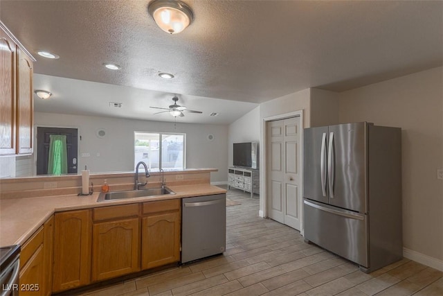 kitchen featuring a peninsula, light wood-style floors, ceiling fan, a sink, and appliances with stainless steel finishes