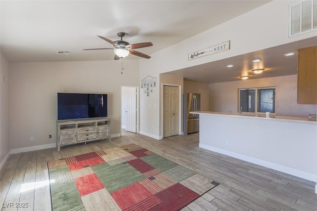 unfurnished living room with a ceiling fan, baseboards, visible vents, and wood finished floors
