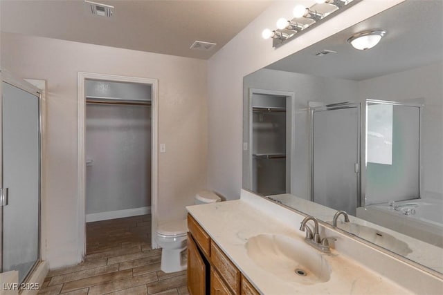 bathroom with visible vents, vanity, wood finished floors, toilet, and a shower stall
