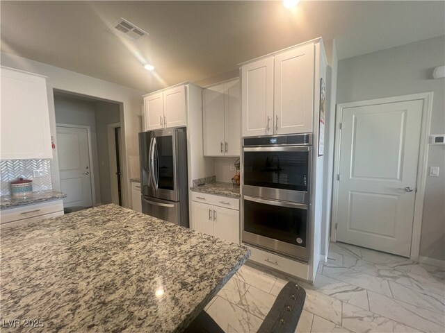 7527 Ardenno St, North Las Vegas, NV 89084 - kitchen featuring stainless steel appliances, light marble finish floors, white cabinetry, and light stone countertops