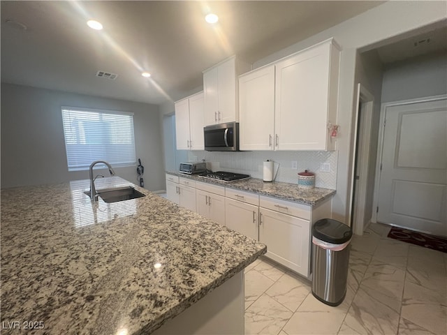 7527 Ardenno St, North Las Vegas, NV 89084 - kitchen with stainless steel microwave, a sink, light marble finish flooring, white cabinets, and recessed lighting