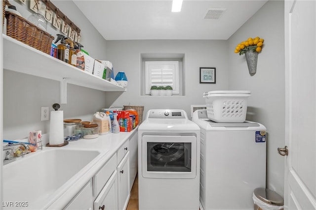 laundry room featuring visible vents, a sink, cabinet space, and washing machine and clothes dryer