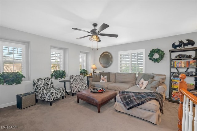 carpeted living area featuring baseboards, a ceiling fan, and a wealth of natural light