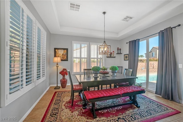 dining space with a raised ceiling, a wealth of natural light, and visible vents
