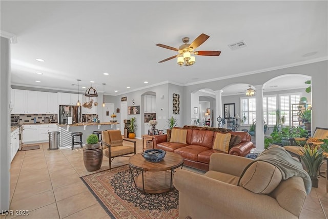 living area featuring ornate columns, arched walkways, visible vents, and light tile patterned floors