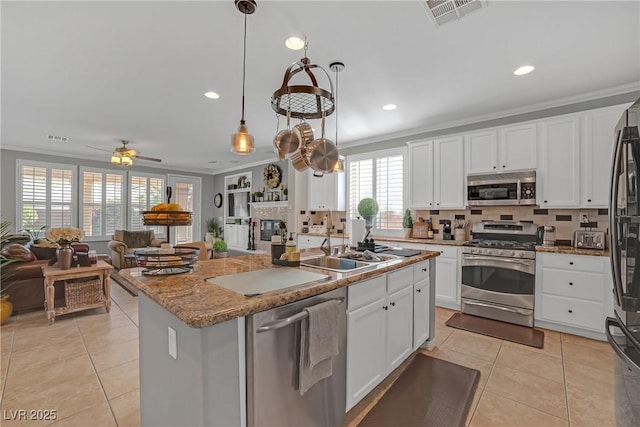 kitchen featuring open floor plan, an island with sink, light tile patterned floors, appliances with stainless steel finishes, and backsplash
