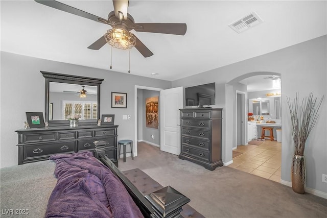 carpeted bedroom with arched walkways, baseboards, visible vents, and ceiling fan
