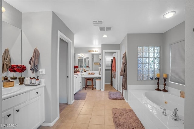 full bathroom with two vanities, tile patterned floors, visible vents, and a tub with jets