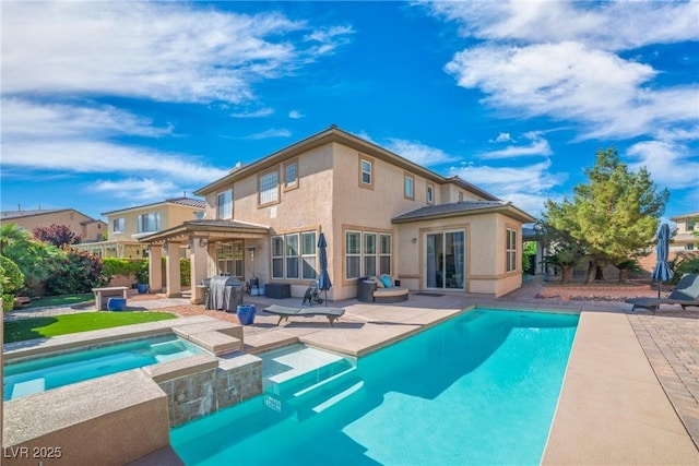 rear view of house with a patio area, stucco siding, and a pool with connected hot tub