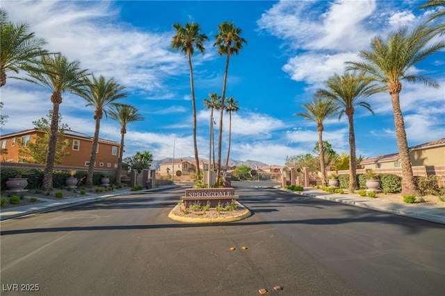 view of road with a gated entry, a residential view, sidewalks, and curbs