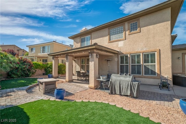 back of house with a lawn, a patio, and stucco siding