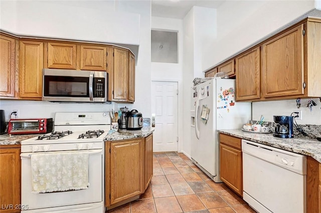 7874 Trail Boss Ct, Las Vegas, NV 89113 - kitchen with white appliances, brown cabinetry, and light tile patterned floors