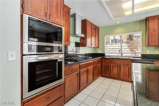 kitchen featuring a sink, wall chimney exhaust hood, dark stone counters, light tile patterned floors, and black appliances