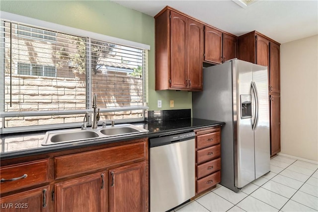 kitchen with a sink, dark countertops, light tile patterned floors, and stainless steel appliances