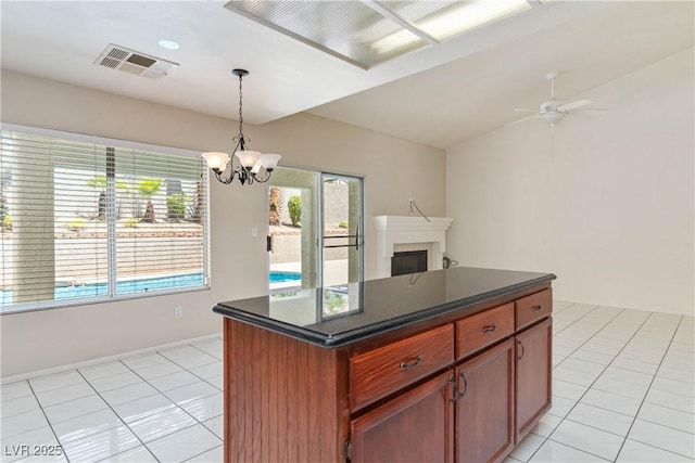 kitchen with decorative light fixtures, visible vents, dark countertops, a fireplace, and light tile patterned floors