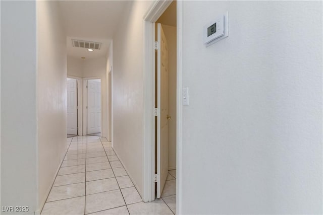 hall with visible vents, baseboards, and light tile patterned floors