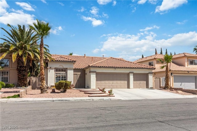 mediterranean / spanish house with a garage, stucco siding, concrete driveway, and a tile roof