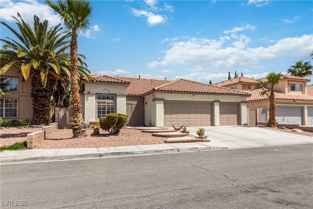 mediterranean / spanish home with a tile roof, an attached garage, driveway, and stucco siding