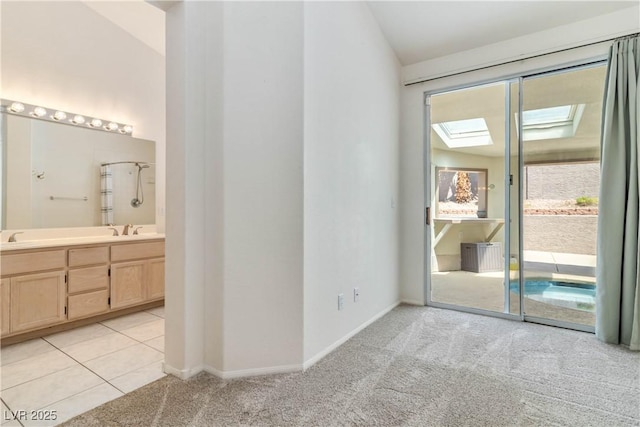 interior space featuring a sink, light carpet, a skylight, and access to exterior