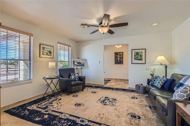 living area with a ceiling fan and baseboards