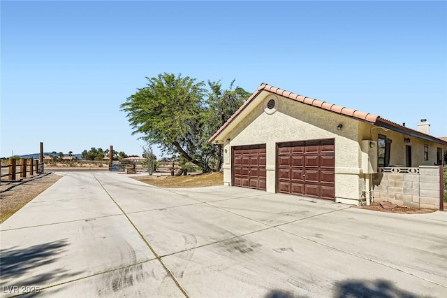 view of home's exterior featuring concrete driveway, an attached garage, a tile roof, and stucco siding