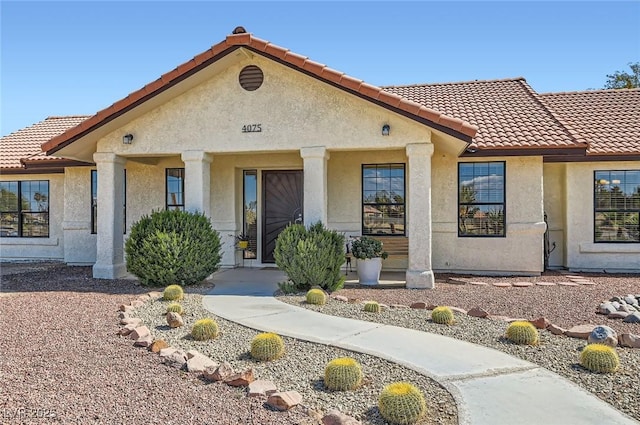 view of front of home featuring stucco siding, a porch, and a tiled roof