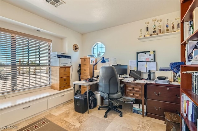 office area featuring visible vents and stone finish floor