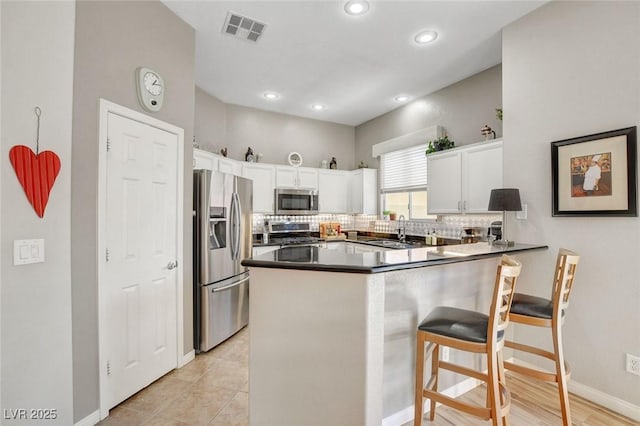 kitchen with backsplash, visible vents, a sink, a peninsula, and stainless steel appliances
